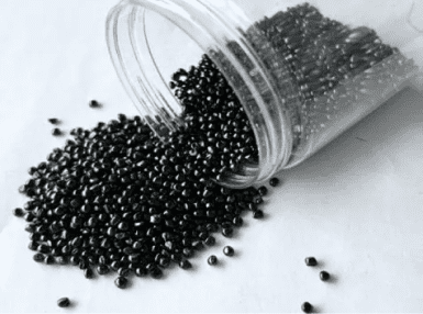 A plastic container filled with black beads on top of the ground.